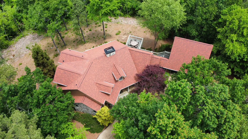 Aerial view of a completed red shingle roof surrounded by trees