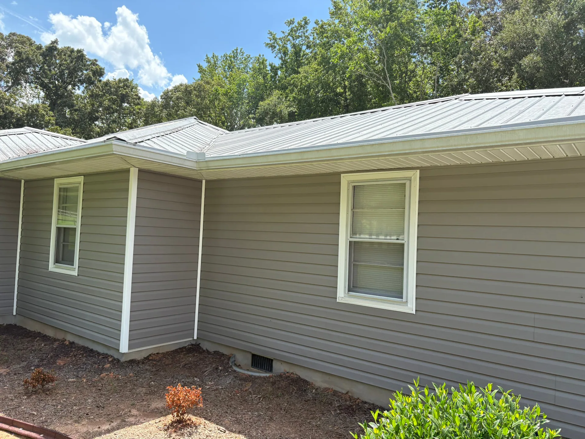 Completed light metal roof on a gray-sided residential home