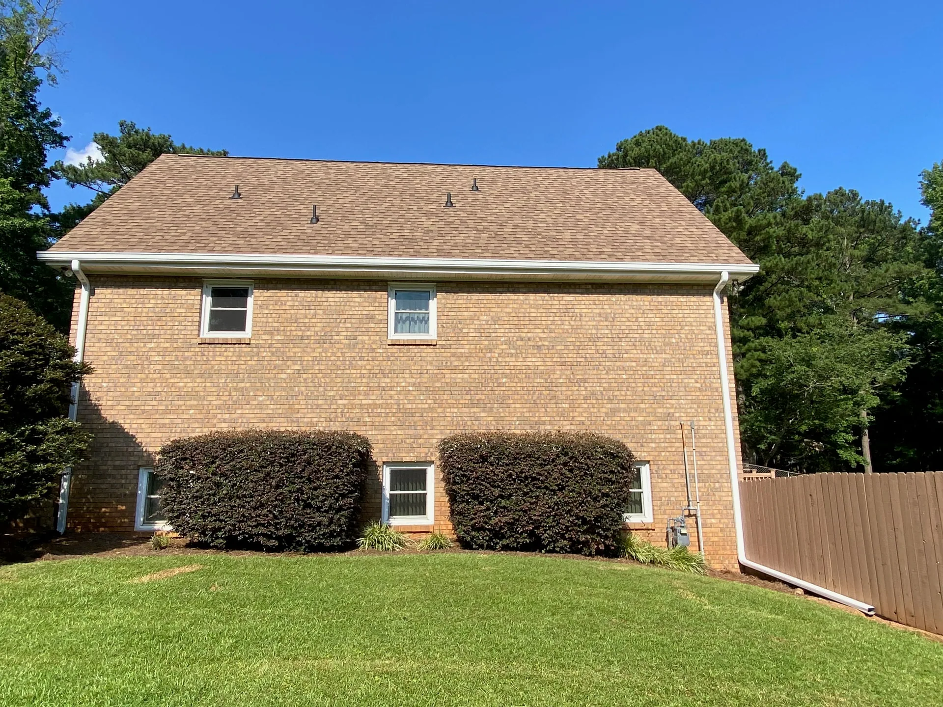 Completed brown shingle roof on a two-story brick home