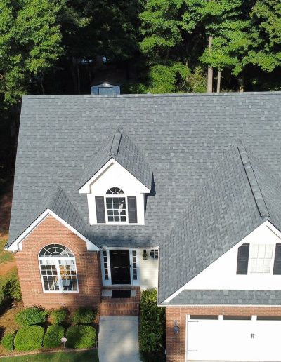 Charcoal shingle roof on brick colonial with landscaped yard